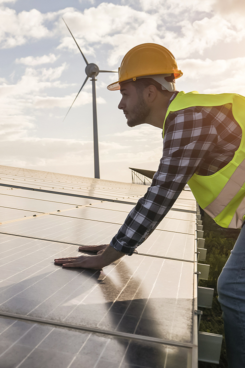 Man working for solar panels and wind turbines - Renewable energy concept