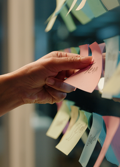 Hand, business and sticky note with planning, ideas and creativity for novel and schedule for writing. Person, closeup or author with brainstorming or research for project, paper or story development